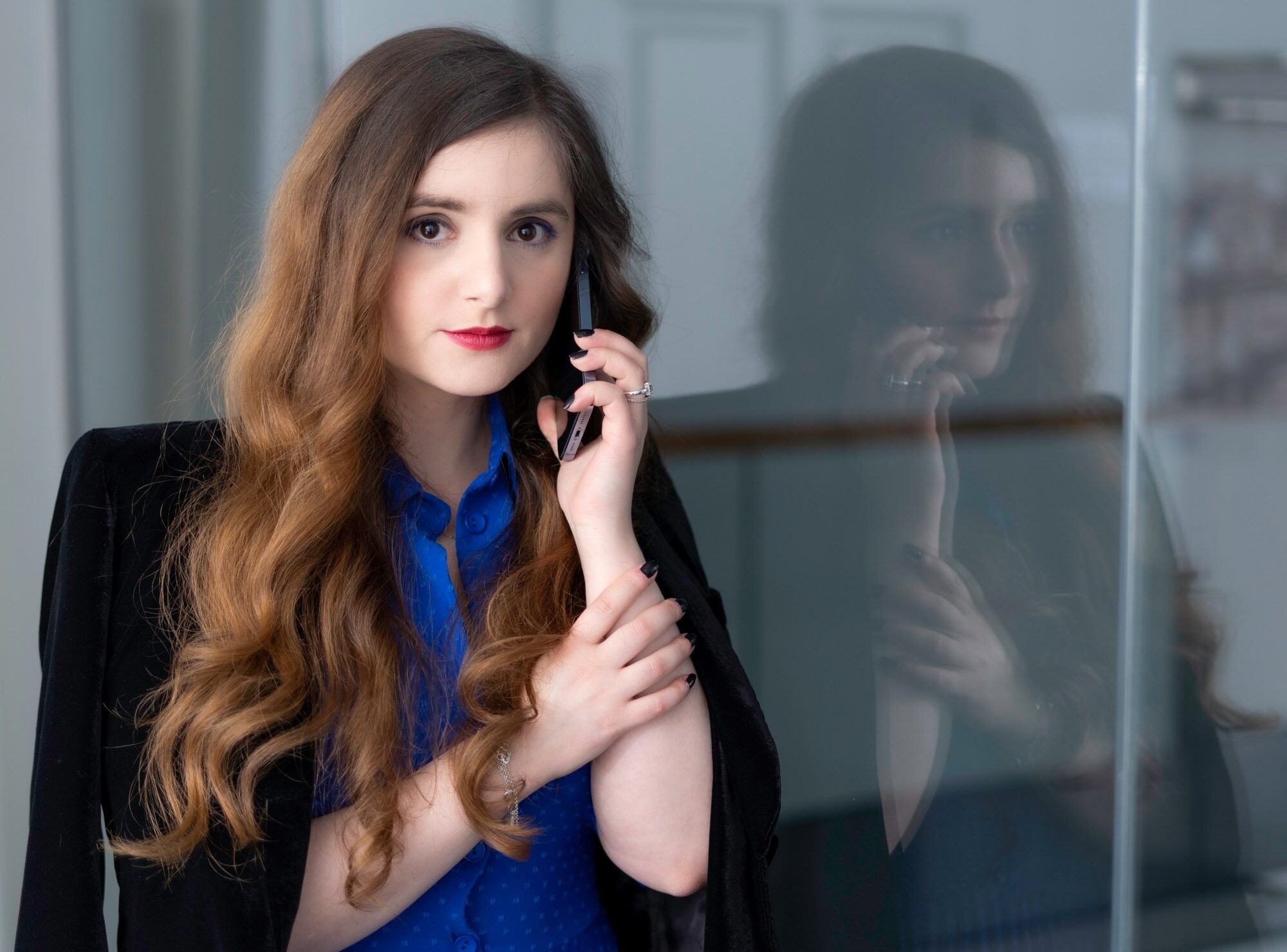 Frau im blauen Kleid und schwarzem Blazer die am Telefon spricht